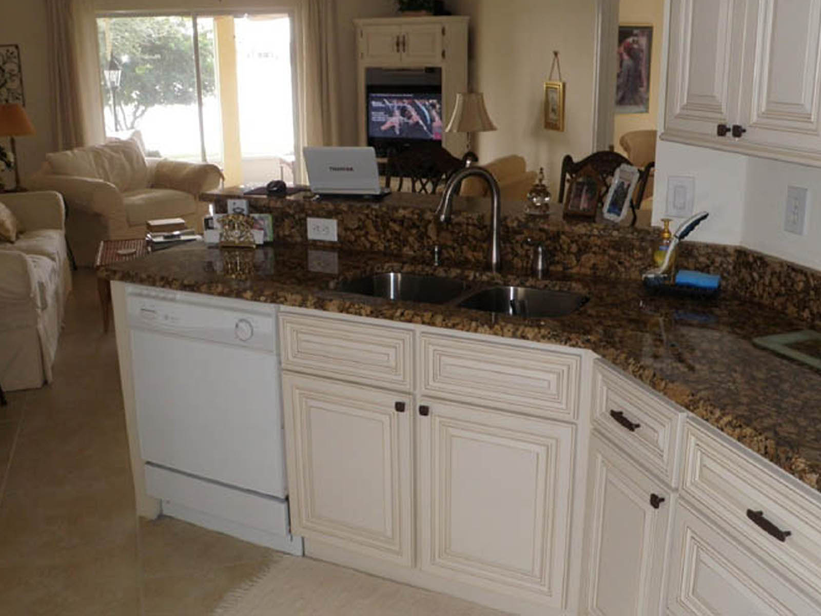 Kitchen with granite countertops before a living room with couches around a tv